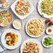 A table with plates of Barilla Three Cheese Tortellini and other foods.