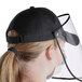 A woman wearing a black Choice 6-panel cap with detachable face shield.