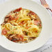 A white plate of Barilla gluten-free fettuccine with mushrooms and cheese.