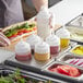 A person using a Choice stainless steel six hole squeeze bottle holder over a counter with a sandwich.