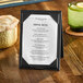 A black table tent with a menu on a table.