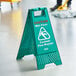 A person standing next to a green Lavex Caution Wet Floor sign.