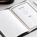 A white table with a menu held together with a gold elastic band.