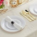 A white table setting with Visions white plates, gold and silver flatware, and a rolled napkin.