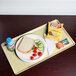 A Cambro lemon chiffon dietary tray with a sandwich, chips, and a blue drink on it.