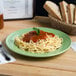 A Tuxton DYA-112 china plate with spaghetti and bread on a table.