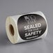 A roll of TamperSafe round black paper labels with white text reading "Sealed For Your Safety"