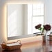 A Bobrick reversible LED backlit surface mounted mirror on a table in a white room.