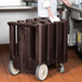 A chef putting a white plate in a brown plastic Cambro dish dolly.