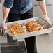 A person using a Choice aluminum baking and roasting pan to cook chicken on a metal grate.