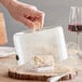 A hand holding a Breville glass cover over a piece of food.