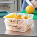 A woman cutting oranges into a Vigor translucent square food storage container.