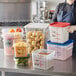 A woman holding a Vigor translucent square polypropylene food storage container of shredded cheese in a kitchen.