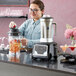 A woman using an AvaMix commercial blender to make a smoothie.