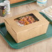 A Choice Kraft paper take-out container with food inside on a tray.