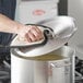 A person using a towel to clean a Choice aluminum pot lid.