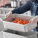 A person holding a Vigor stainless steel hotel pan full of carrots.