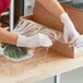 A person in gloves wrapping a box with Western Plastics perforated plastic wrap.