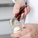 A person using a Vollrath #70 brown squeeze handle disher to scoop ice cream into a cup.