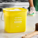 A yellow Noble King-Pail 6 quart multi-purpose cleaning pail filled with soapy water.