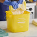 A yellow Noble King-Pail 8 quart multi-purpose cleaning pail being used with a sponge and gloves.