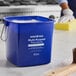A blue Noble King-Pail 6 quart multi-purpose cleaning pail filled with soapy water.