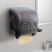 A black plastic San Jamar paper towel dispenser mounted on a wall.