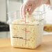 A person in plastic gloves adding cheese to a Carlisle clear polycarbonate food storage container.