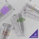 A group of clear Acopa Endure stackable plastic glasses with a purple logo.