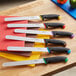 A Schraf serrated slicing knife with a red handle on a cutting board.