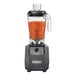 A Hamilton Beach food blender with a clear container filled with orange liquid.