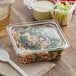 A Dart plastic container of vegetables in white sauce on a counter.