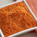 A white square bowl of orange Backyard Pro Chesapeake seasoning.