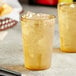 Two Choice amber plastic tumblers filled with ice and liquid on a table.