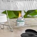 A can of wick chafing dish fuel with a safety twist cap placed under a metal rack supporting an aluminum tray.