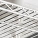 A white metal rack with wires holding white bins.