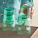 A woman holding two green Choice plastic tumblers.