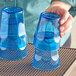 A person holding two blue Choice plastic tumblers.