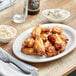 A plate of chicken wings with a bottle of Backyard Pro Creole Seasoning Blend on a table.