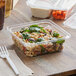 A white plastic fork on a table with a Dart TamperGuard plastic container of food.