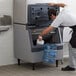 A man putting ice into a Scotsman ice storage bin.