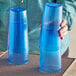 A person holding two blue Choice plastic tumblers.