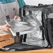 A man using a ServIt large square backpack delivery bag to hold a pizza box.
