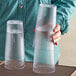 A hand holding a stack of Choice clear plastic tumblers.