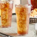 Two Choice clear plastic tumblers filled with ice tea on a table.