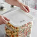 A person holding a white Vigor polypropylene food storage container with pasta.