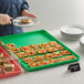 A person holding a plate with food on a green Choice bakery display tray.