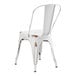 A white metal Lancaster Table & Seating outdoor cafe chair with a brown distressed finish.