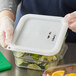 A person holding a white Vigor square polypropylene container filled with limes.