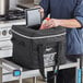 A man in a chef's uniform using a Vollrath insulated milk crate bag to hold a bottle of milk.